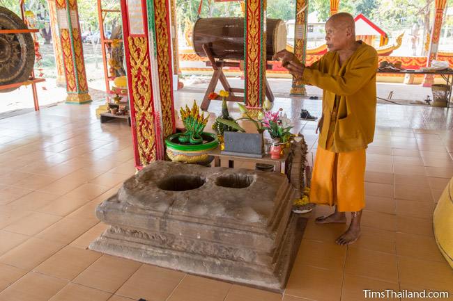 thai buddhist monk standing next to sandstone pedestal of Ku Bueng Jiew Khmer ruin