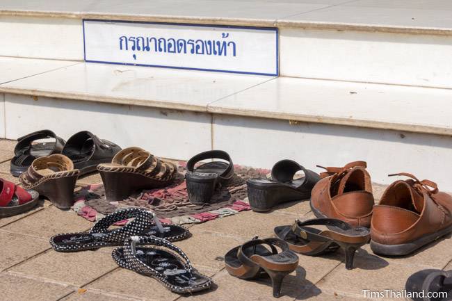 shoes and please take off your shoes sign at shrine in Thailand