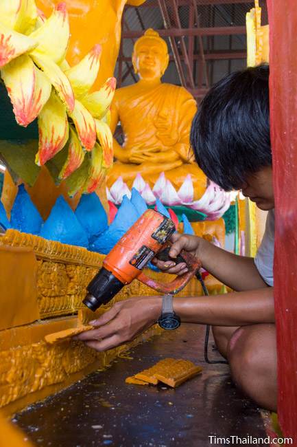 man using heat gun to make a Khao Phansa candle parade float