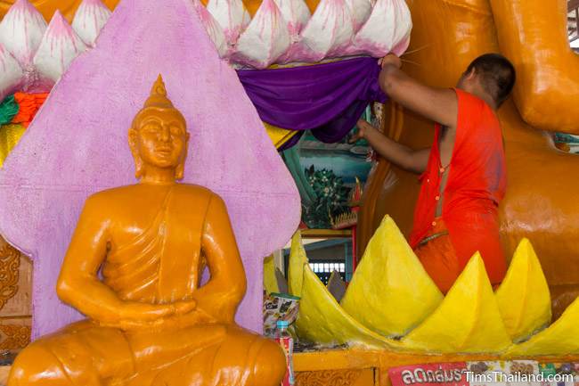 monk hanging fabric on a Khao Phansa candle parade float