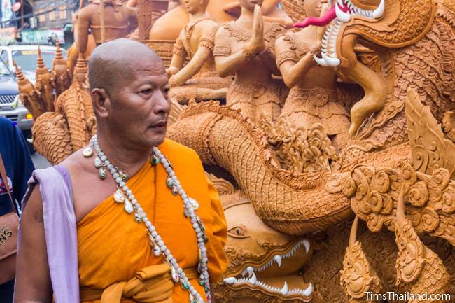 monk standing next to a Khao Phansa candle parade float