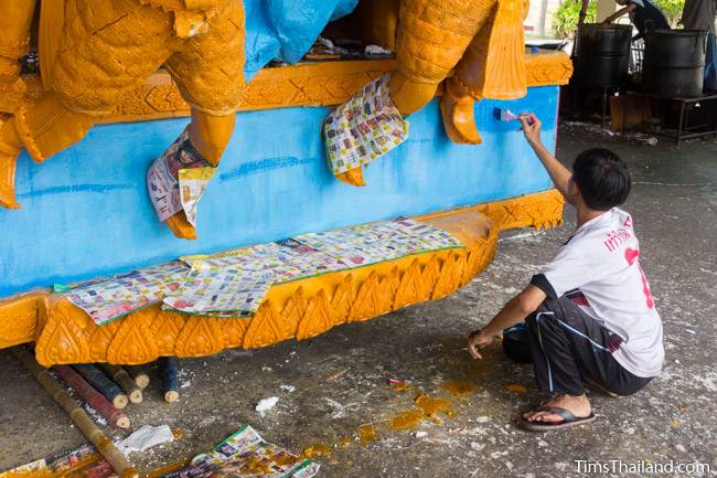 man painting blue wax on a Khao Phansa candle parade float