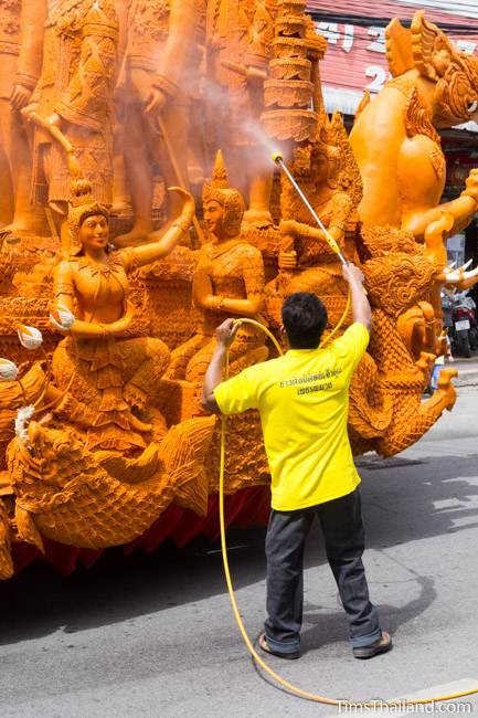 man spraying water on a Khao Phansa candle parade float