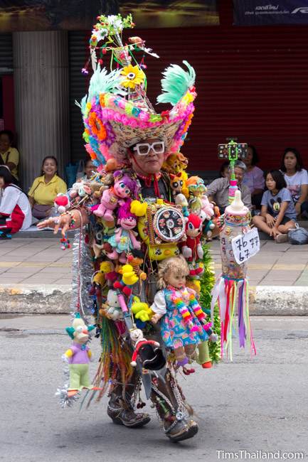 man wearing suit made of dolls in Khao Phansa candle parade