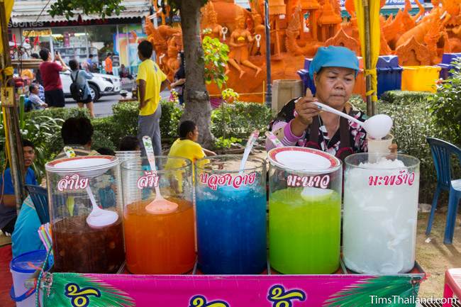 woman selling drinks in front of a Khao Phansa candle parade float