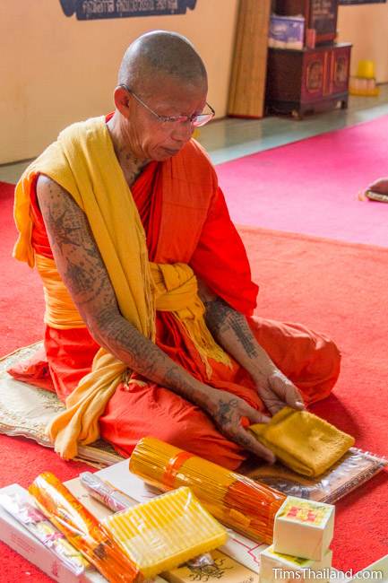 tattooed monk with offerings in front of him