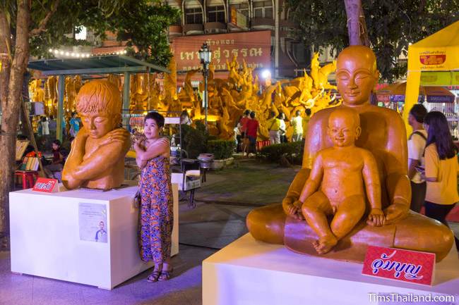 wax sculptures in front of a Khao Phansa candle parade float