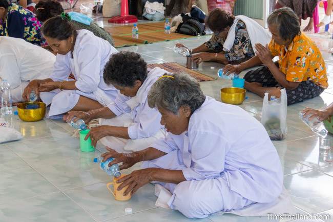 women in white pouring holy water