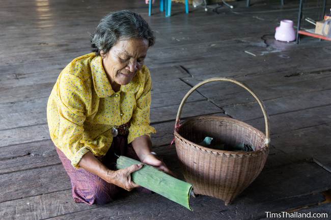 woman wrapping fish in a banana leaf