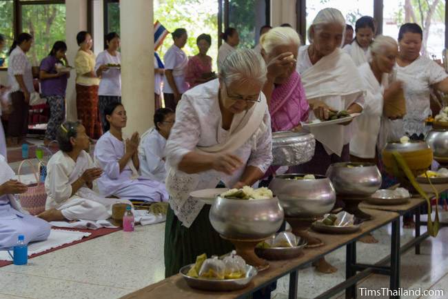 people giving food to the monks during Boon Khao Pradap Din