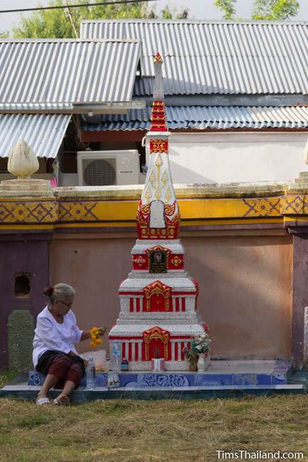 woman cleaning funerary stupa during Boon Khao Pradap Din