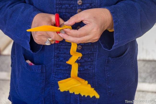 woman cutting paper to make lantern for Kathin celebration