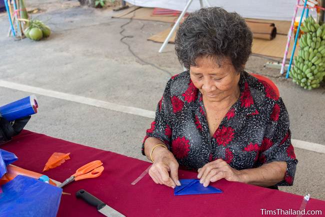 woman folding paper to make lantern for Kathin celebration