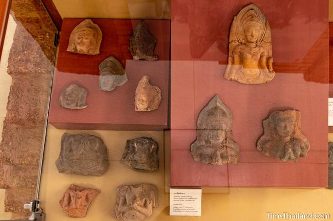 12 antefix tiles in a glass display case