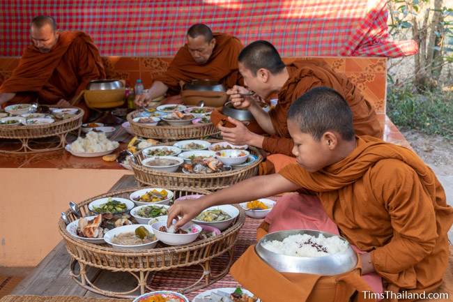 monks eating off of big trays at Boon Berk Bahn