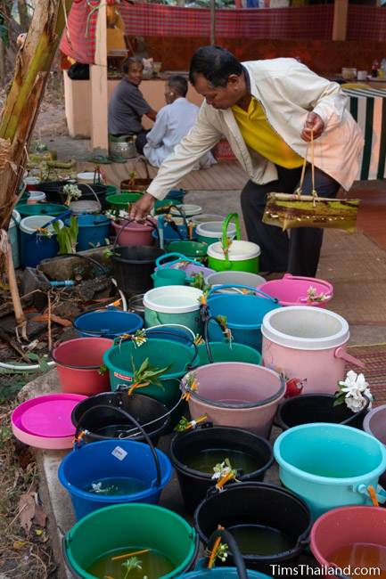 man putting kratong and scented water bucket on the ground at Boon Berk Bahn