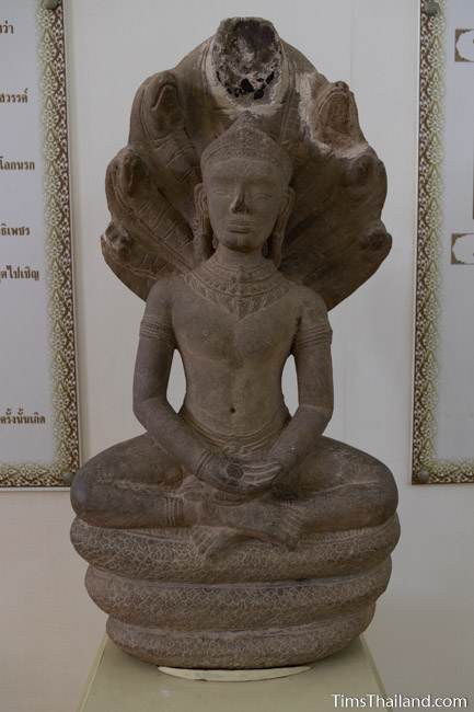 Buddha meditating under a naga stone carved statue