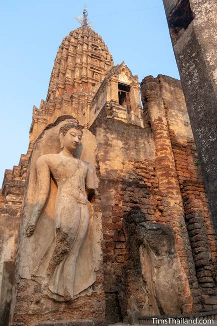 Sukhothai-style walking Buddha in front of prang