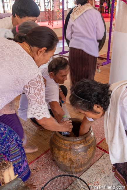 people taking water out of a big jar