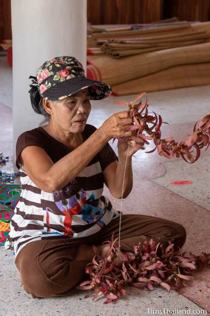 woman making garland our of tree seeds