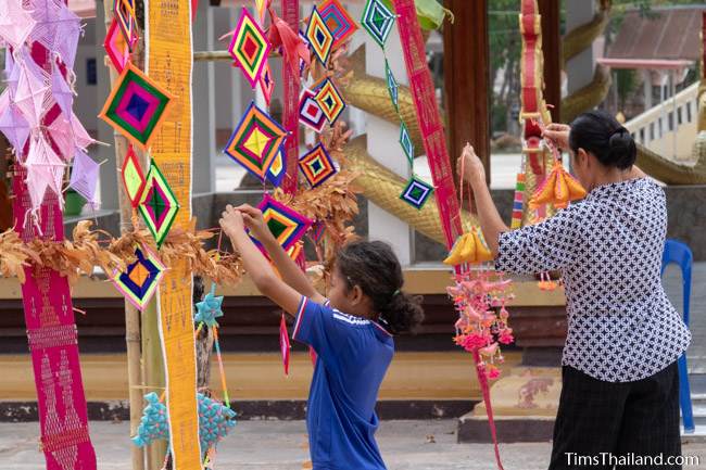 woman and girl hanging decorations outside wihan