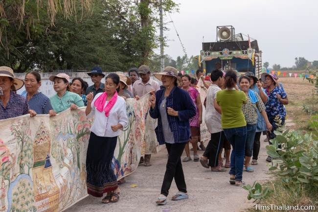 people carrying Pha Wet banner through village
