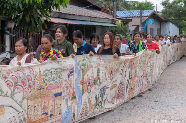 people carrying Pha Wet banner through village