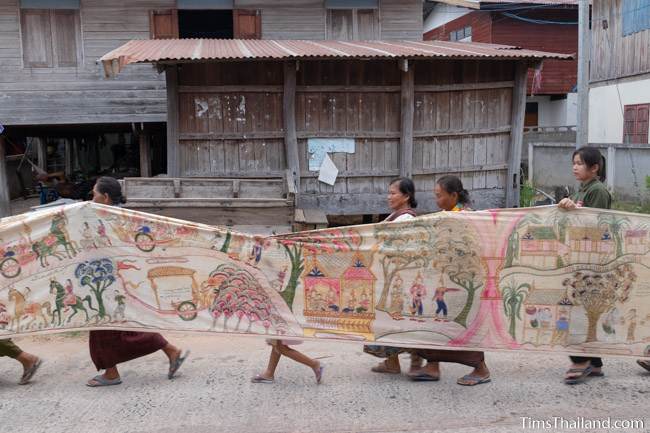 people carrying Pha Wet banner through village