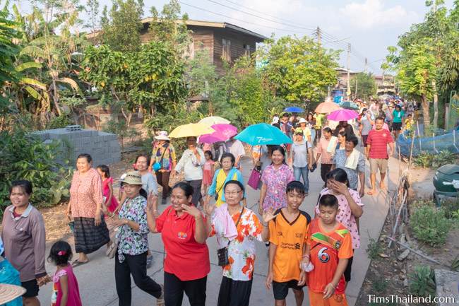 long line of people walking through village