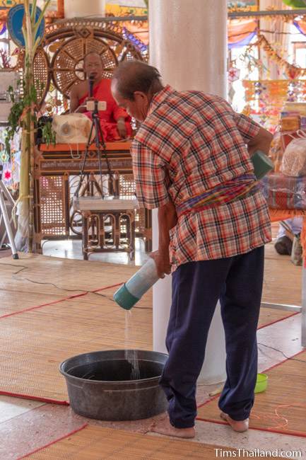 man pouring water into bucket