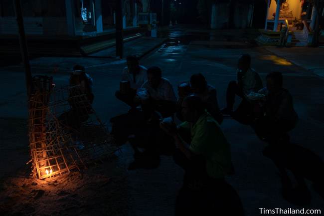 people praying at night in front of a candle