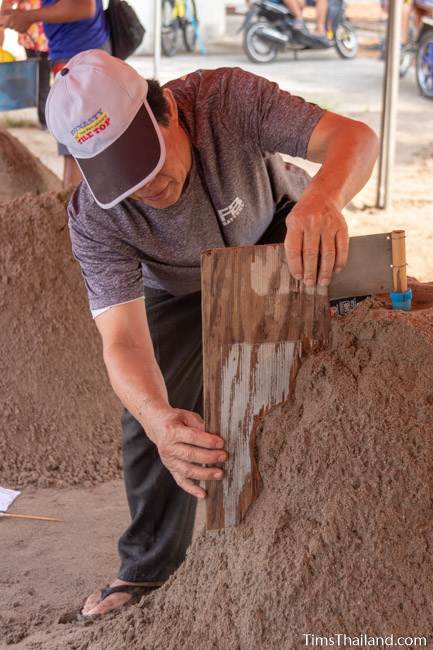 using template to shape sand on a sand stupa