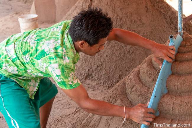 using template to shape sand on a sand stupa