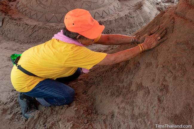 patting down sand on a sand stupa