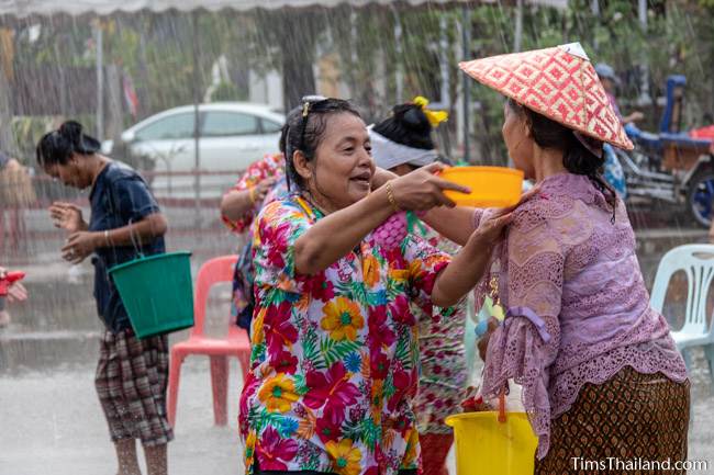 two women pouring water over each other's shoulders