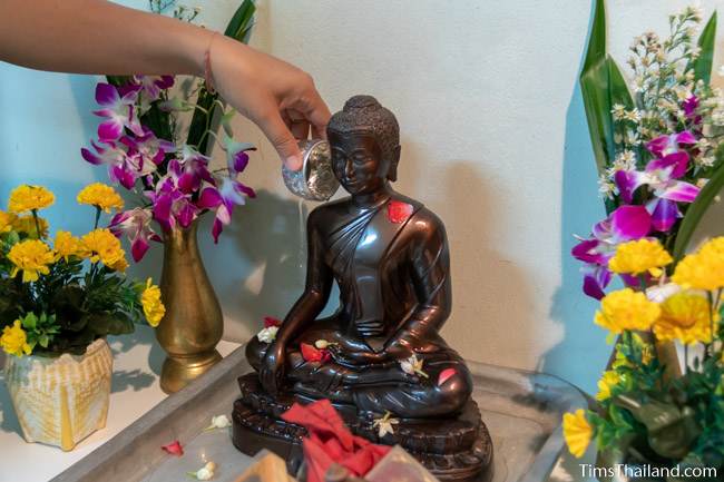 pouring water on Buddha at a house