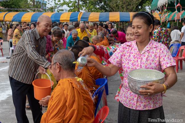 men and women pouring water on monks