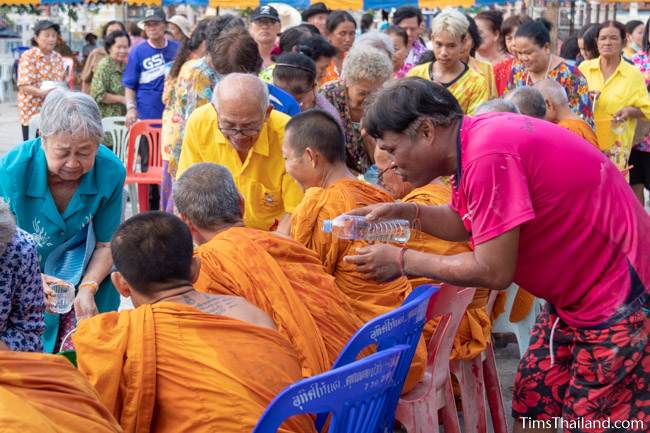 men and women pouring water on monks