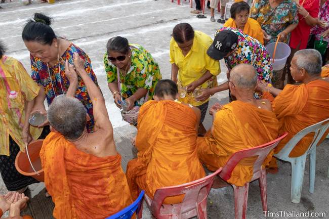 men and women pouring water on monks