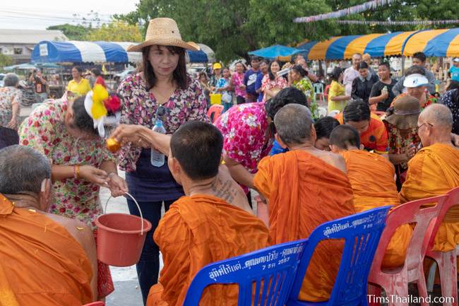 men and women pouring water on monks