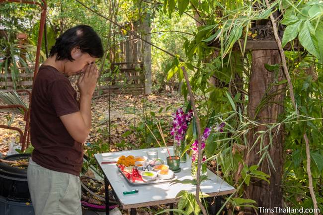 praying before a spirit house