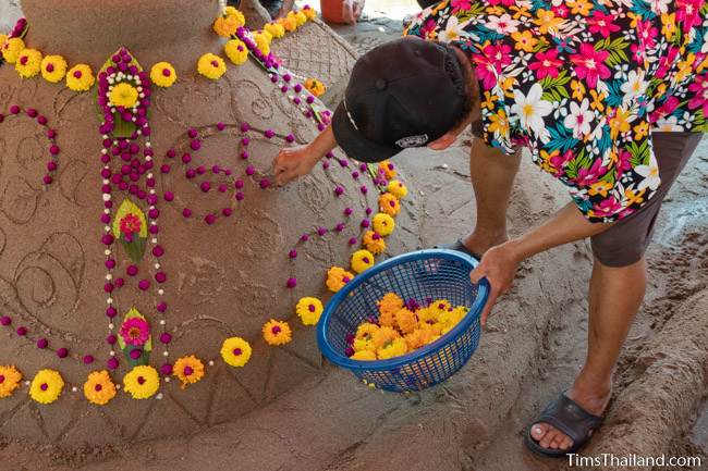 woman putting flowers on sand stupa