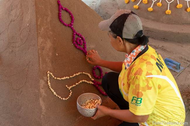 woman putting flowers on sand stupa