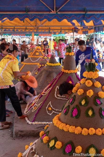 women putting flowers on sand stupa