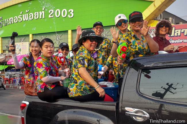 people in colorful shirts sitting in back of a pickup truck