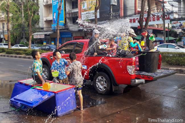 people on the street and in a truck throwing water at each other