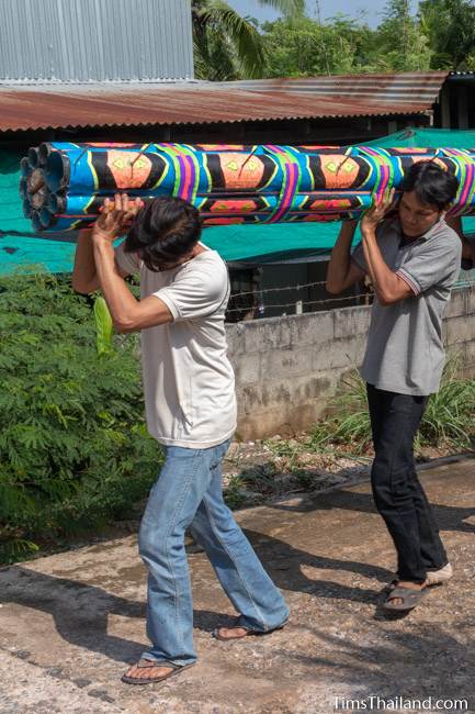 men carrying a mock rocket for a parade float