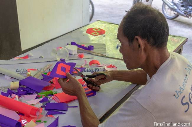 man cutting paper for a parade float