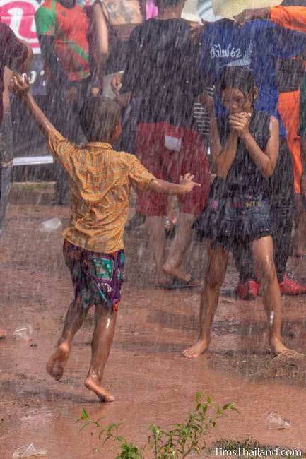 children dancing as water falls on them