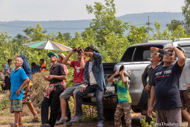 men sitting on a pickup truck looking up to the sky